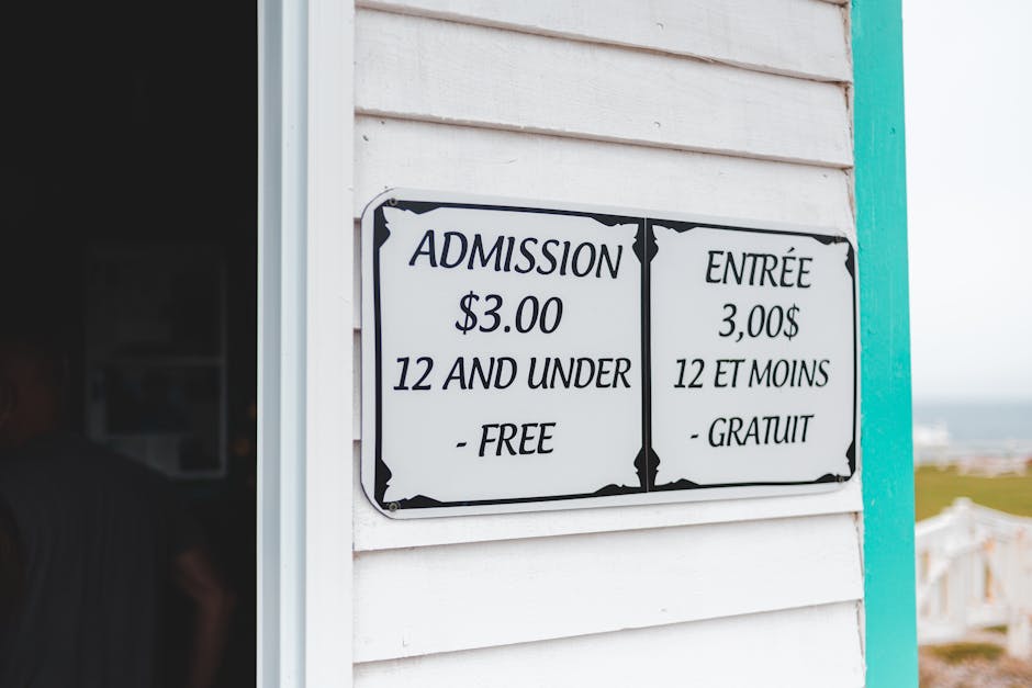 A rectangular white sign with black decorative borders mounted on a white wooden wall, displaying flower delivery pricing for Kingston. The sign features bilingual text in English and French, indicati